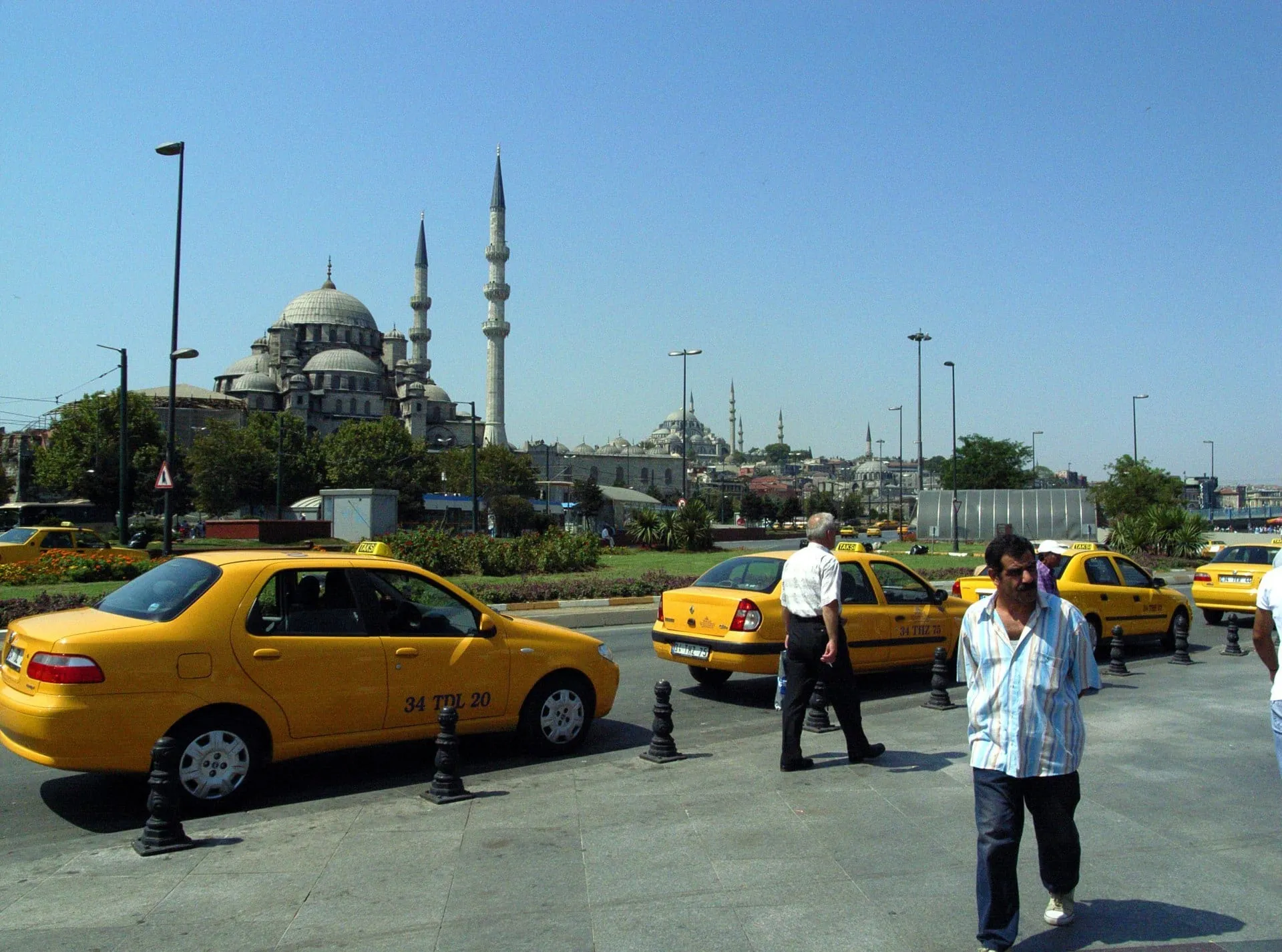 Gelbe Taxis stehen vor einer Moschee mit ihren Minaretten.