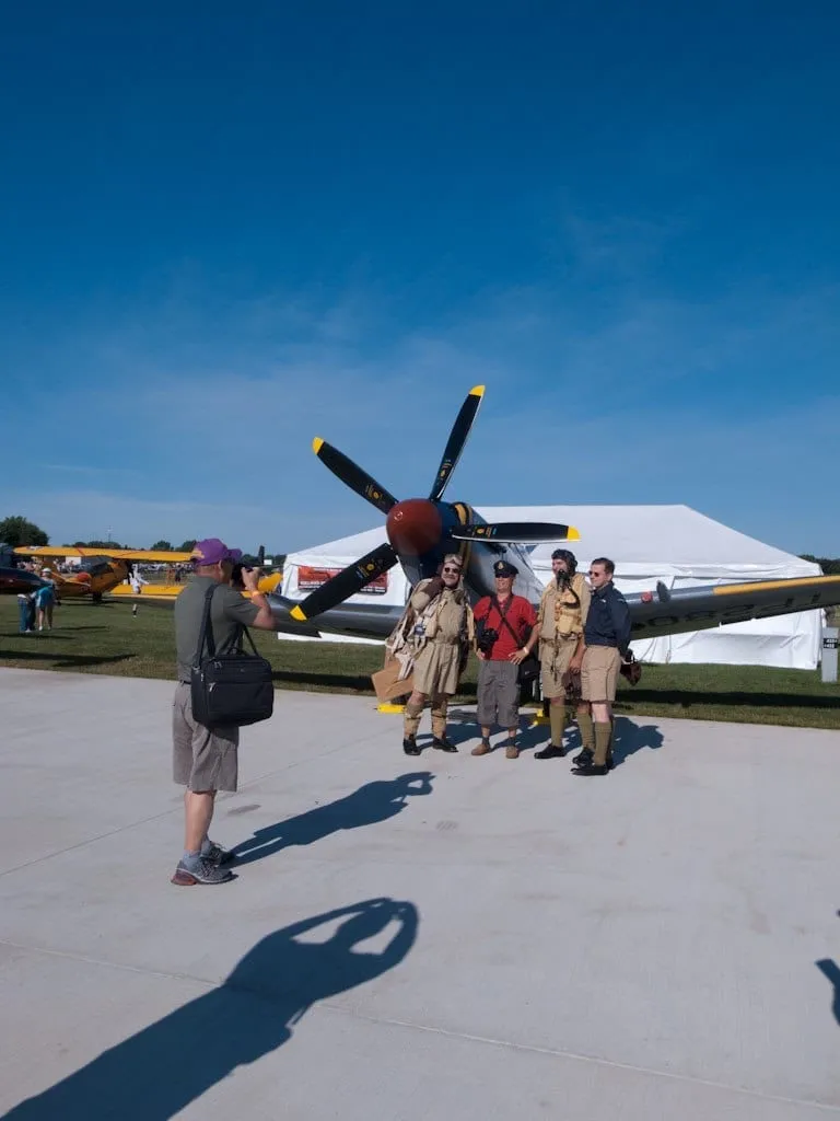 Besucher fotografieren einen historischen Propellerjäger auf dem Vorfeld.